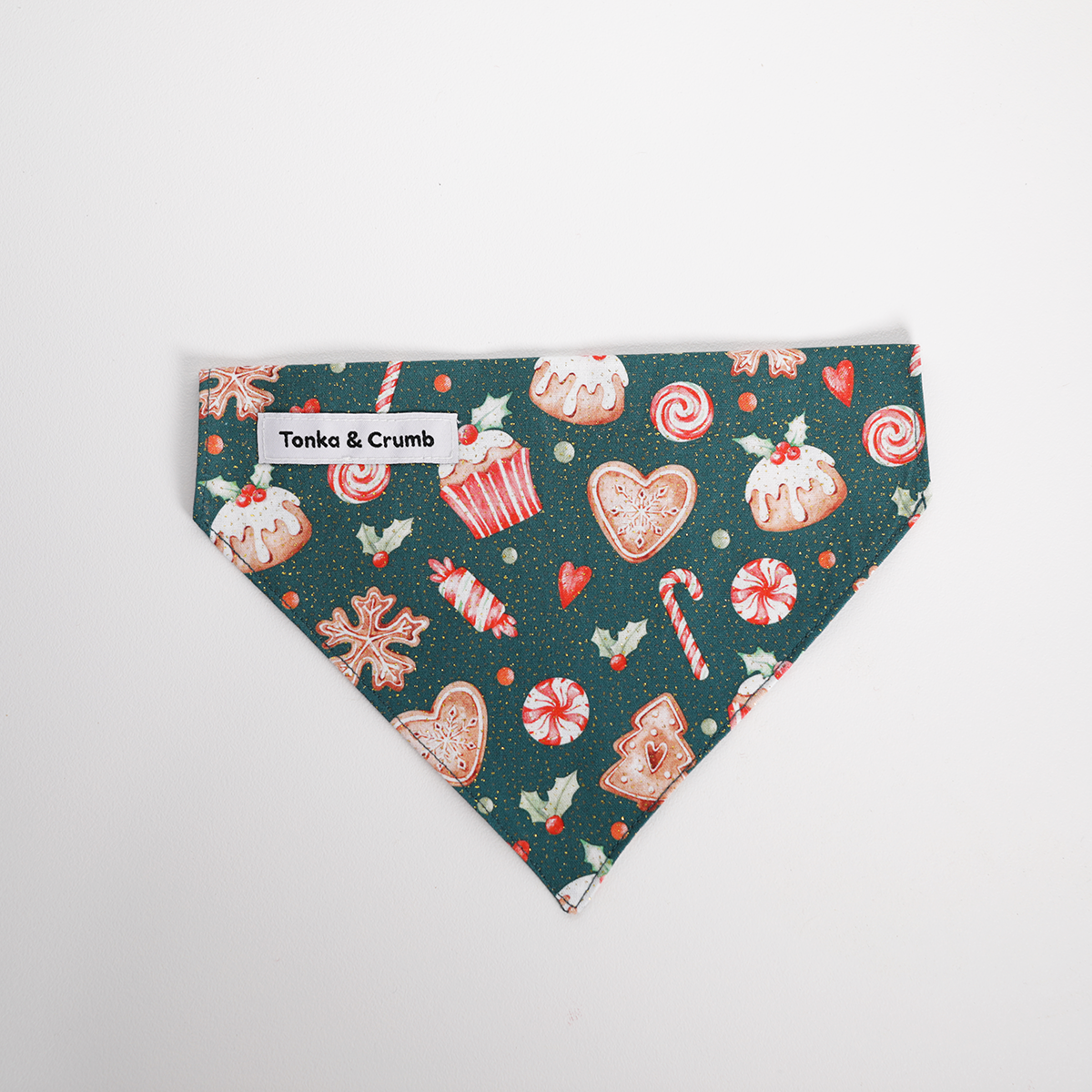 Christmas-themed dog bandana with candy cane, gingerbread, and cake designs on a green background.
