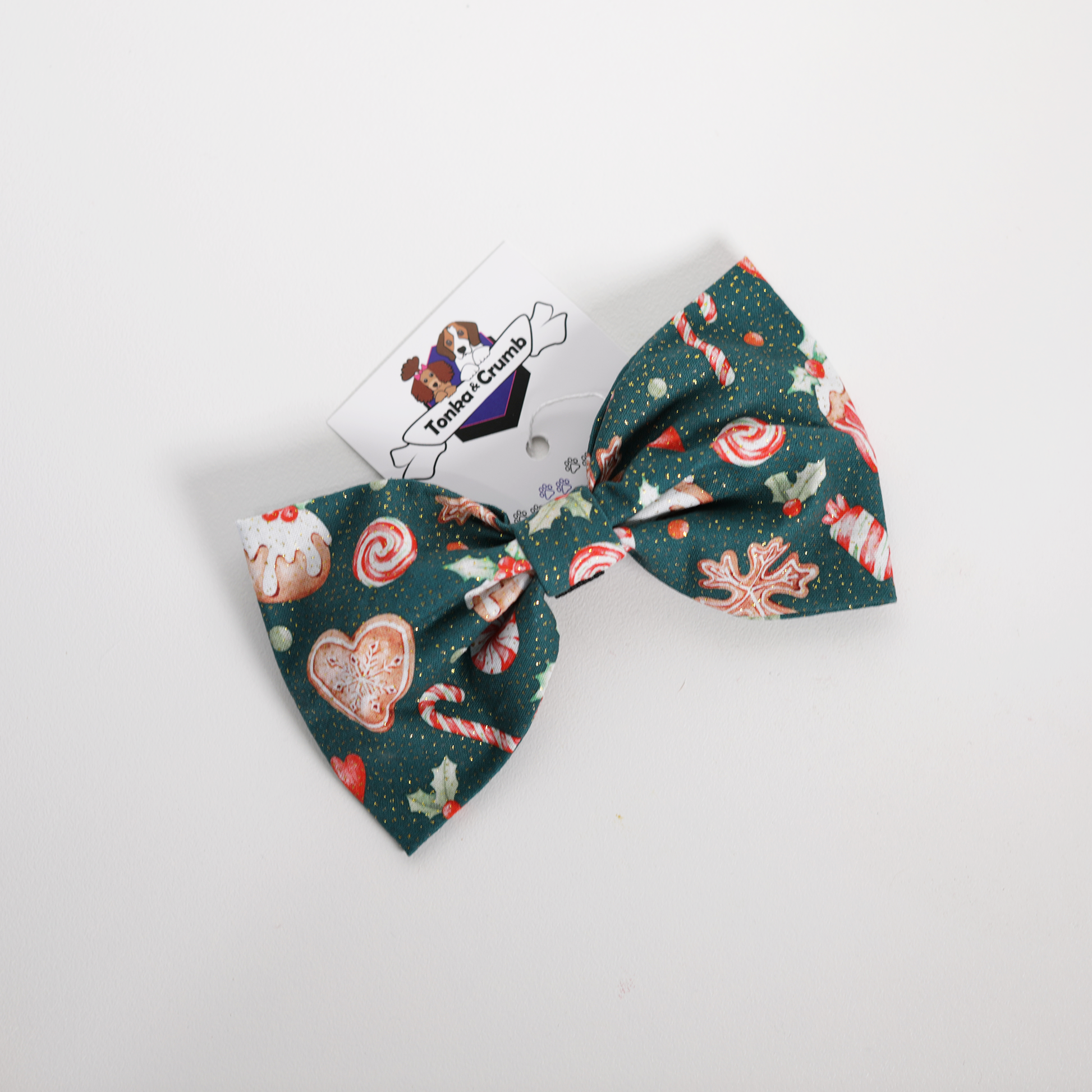 Christmas-themed dog bow tie with candy cane and gingerbread design on a white background